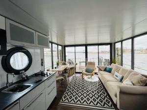 a living room with a couch and a kitchen with windows at Hausboot Hafenprinz Lübeck in Brodten