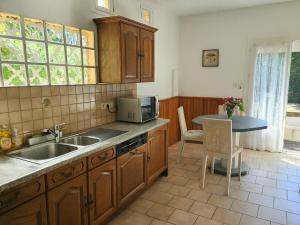 a kitchen with wooden cabinets and a sink and a table at Maison confortable avec 3 chambres et jardin clos, idéale familles et curistes à Salies-de-Béarn in Salies-de-Béarn