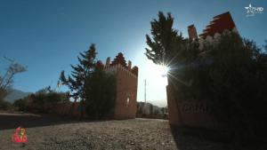 a building with the sun shining behind it at Camping Granit Rose in Tafraoute