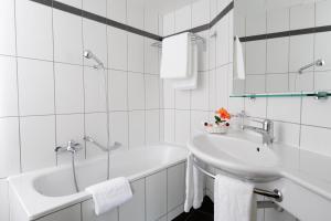 a bathroom with a sink, mirror, and bathtub at Hotel Eden in Geneva