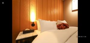 a bedroom with a bed with white sheets and a lamp at 12번길stay  +13 photos