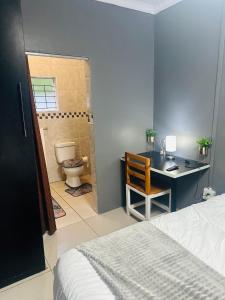 Schlafzimmer mit einem Bett, einem Schreibtisch und einem WC in der Unterkunft SerenityStay 37 on Zebra in Polokwane