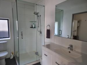 a bathroom with a sink and a shower with a mirror at Rosandra Retreat in New Plymouth