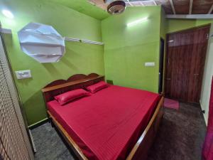 a bedroom with a bed with red sheets and green walls at Coorg Coffee Tales in Suntikoppa