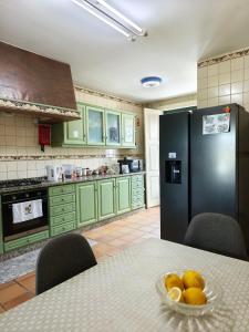 a kitchen with green cabinets and a table with a bowl of fruit at Donna Nega Guest House in Caminha