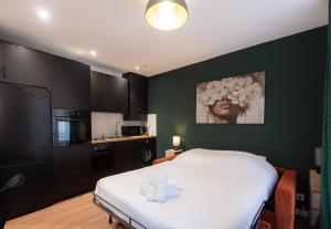 a bedroom with a white bed and a kitchen at Studio rénové - Accès direct Paris in Montreuil +3 photos