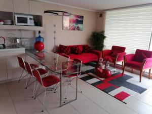 a living room with a glass table and red chairs at Vista velero in Algarrobo