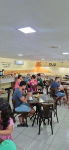 grupa ludzi siedząca przy stołach w restauracji w obiekcie Apartamento a beira mar w mieście Natal