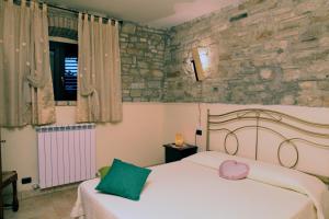 1 dormitorio con cama y pared de piedra en Il Casale della Quercia, en Asís