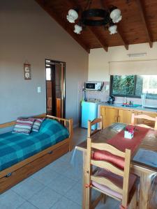 a bedroom with a bed and a table and a kitchen at Cabañas Lemunko in Sierra de la Ventana