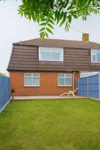 a red brick house with a blue fence and a yard at Spacious 3-Bed Contractor-Friendly Home in Bristol