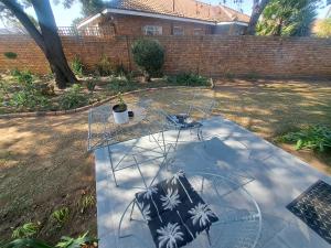 a glass table with a chair in a yard at Dragonfly in Boksburg +2 photos