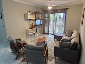 ein Wohnzimmer mit Sofa, Sesseln und Fernseher in der Unterkunft Apto 2 dorm - Requinte na Praia Grande - SP in Praia Grande