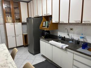 eine Küche mit weißen Schränken und einem Edelstahlkühlschrank in der Unterkunft Apto 2 dorm - Requinte na Praia Grande - SP in Praia Grande