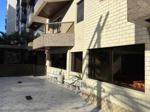 ein Gebäude mit einer Terrasse mit Stühlen und einem Balkon in der Unterkunft Apto 2 dorm - Requinte na Praia Grande - SP in Praia Grande