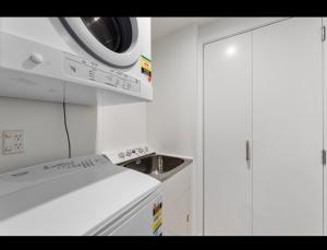 a white kitchen with a stove and a microwave at Beach escape at Mount Maunganui in Mount Maunganui +4 photos