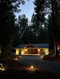 a small house with lights in front of a driveway at The Mossy Nook A Cozy Escape in the Woods! in Issaquah