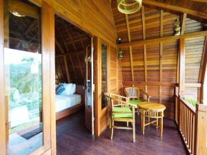 Zimmer mit einem Balkon mit einem Bett, einem Tisch und Stühlen in der Unterkunft Casa Vella Cottage in Patjung