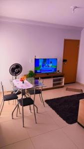 a living room with a table and chairs and a tv at Apartamento de 02 quartos com vista para o lago in Palmas