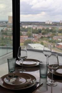 a table with plates and wine glasses on a balcony at Luxury penthouse with the best view in Manchester in Manchester