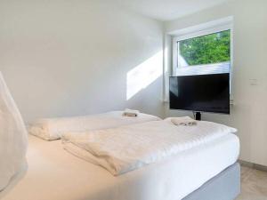 a white bedroom with two beds and a flat screen tv at Holiday apartment with 2 bedrooms in Greetsiel