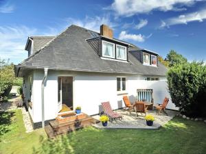 une maison blanche avec 2 chaises et une terrasse dans l'établissement Süderhof Apartment 2, à Keitum