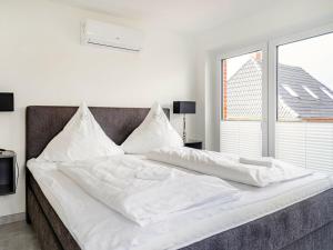 a large bed with white sheets and a window at Holiday apartment with 2 bedrooms in Greetsiel