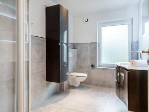 a bathroom with a toilet and a sink and a window at Holiday apartment with 2 bedrooms in Greetsiel +16 photos