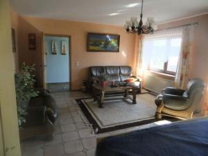 a living room with leather furniture and a table at Holiday apartment Hochwald in Prosterath