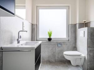 a bathroom with a sink and a toilet and a window at Holiday apartment with 2 bedrooms in Greetsiel