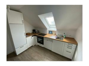 Elle comprend une petite cuisine avec des placards blancs et une fenêtre. dans l'établissement Holiday apartment in Varel with swimming pool, à Dangast