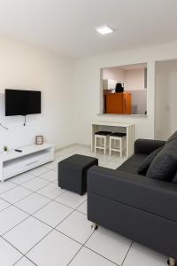a living room with a black couch and a tv at Ar nos 2 quartos e sala in Imperatriz