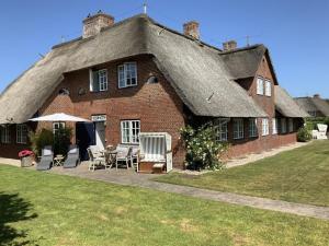 ein großes rotes Backsteinhaus mit einem Strohdach in der Unterkunft Schroeders House Kampen House 1C in Kampen