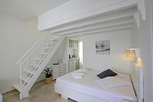 um quarto branco com uma cama branca e uma escada em Glaros Studios em Naxos Chora
