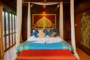 ein Schlafzimmer mit einem Bett mit zwei Schwänen darauf in der Unterkunft Singha Montra Lanna Boutique Style Hotel in Chiang Mai
