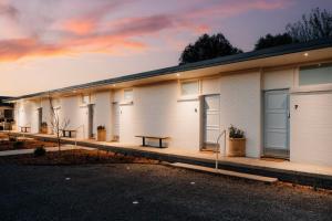a row of white buildings with a bench in front at The Cudgee at Mudgee in Mudgee