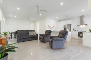ポートダグラスにあるLuxury on Mudlo, 4 bedroom luxury home with heated poolのリビングルーム(椅子2脚、ソファ付)
