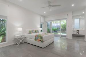 ポートダグラスにあるLuxury on Mudlo, 4 bedroom luxury home with heated poolの白いベッドルーム(ベッド1台、テーブル、窓付) +31枚の写真