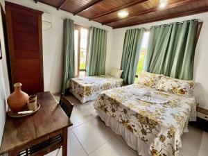 a bedroom with two beds and a table and windows at Casa de Vó in Porto Seguro +20 photos