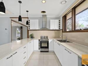 a kitchen with white cabinets and a sink and a stove at Entire House close to Supermarket gym Restaurants in Melton