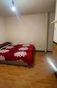 a bedroom with a red bed with white flowers on it at Hostal centro in La Serena