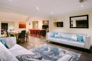 a living room with a couch and a dining room at Fairways - Spacious Pool House by the Golf Course in Dunsborough
