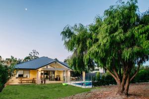 a house with a tree in front of it at Fairways - Spacious Pool House by the Golf Course in Dunsborough