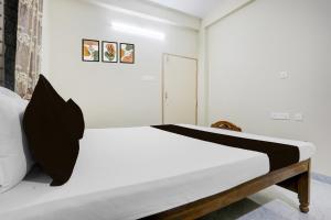 um quarto com uma cama com lençóis brancos e uma porta em Hotel O Kunjaban residency em Cuttack