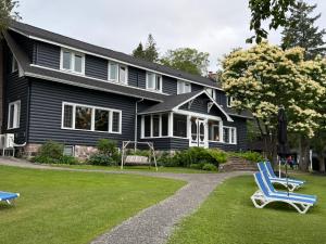 a black house with two blue chairs in the yard at Bonnie View Inn in Haliburton