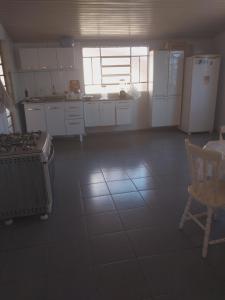 cocina grande con electrodomésticos blancos, mesa y sillas en Casa Aconchegante, en Nova Odessa