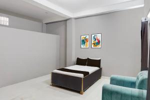 a bedroom with a bed and a blue chair at Hotel O Raj Palace in Bāra Banki