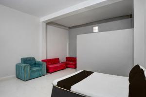 a bedroom with two red chairs and a bed at Hotel O Raj Palace in Bāra Banki