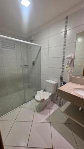 a bathroom with a toilet and a glass shower at Apartamento Barretos Park Hotel in Barretos