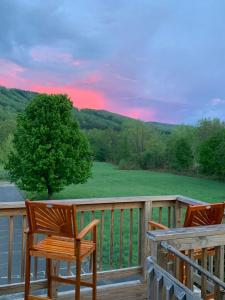 two chairs on a deck with a view of a field at Riverbend Berkshire East Basecamp in Charlemont